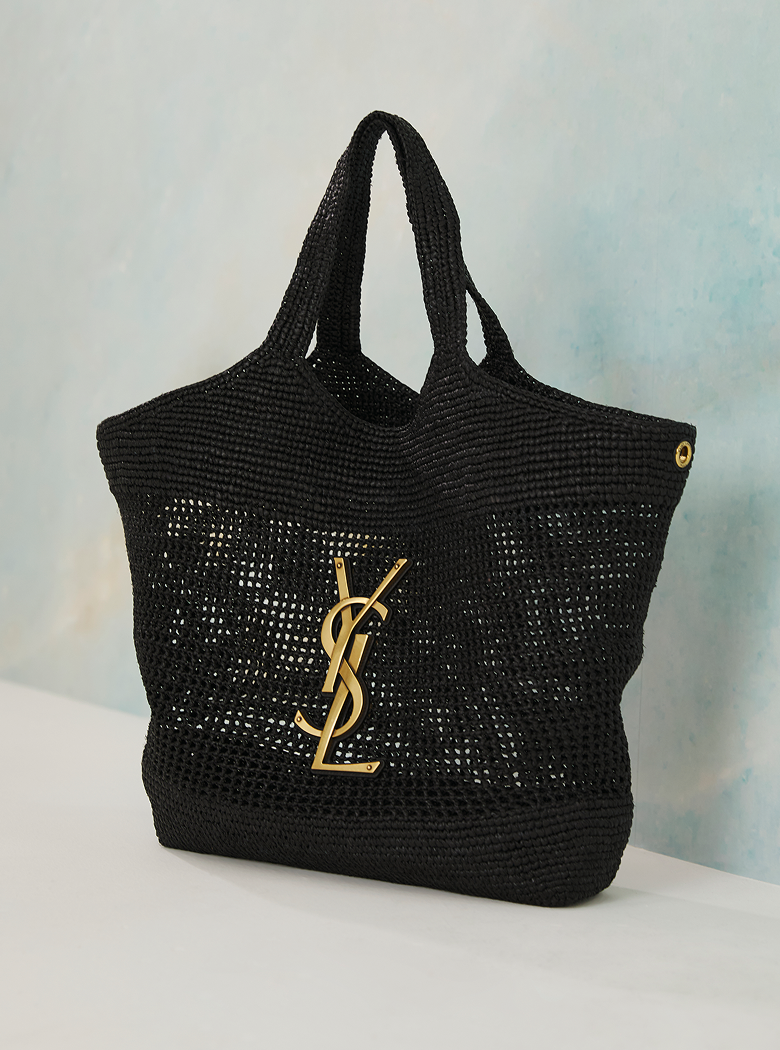 Black woven handbag with a gold logo on a light gray background