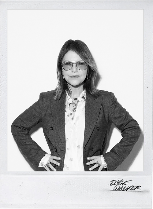 Black and white portrait of a woman wearing glasses and a blazer with a signature at the bottom right corner.