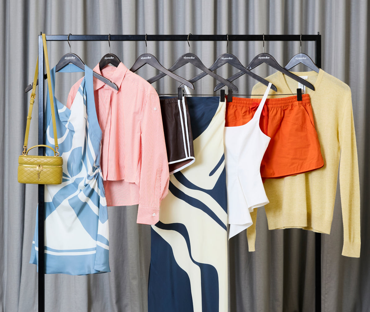 Clothing rack with various garments against a gray curtain background