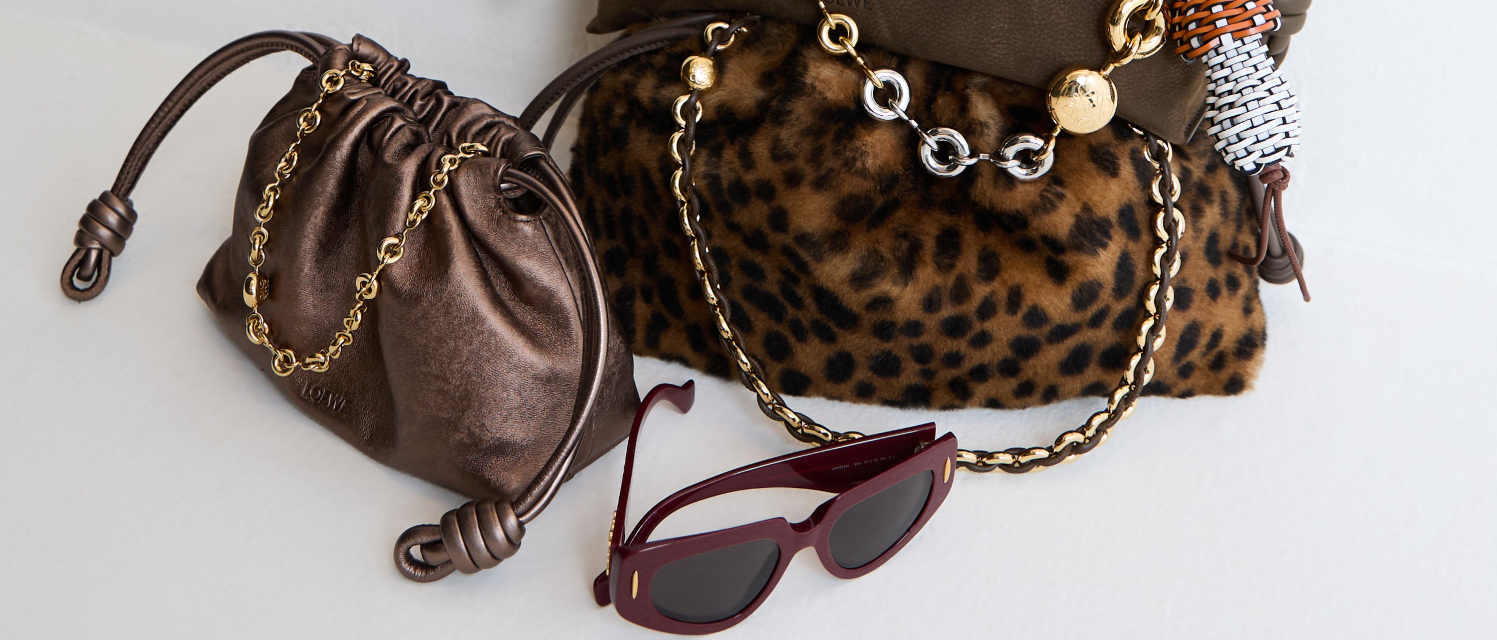 Brown leather pouch, leopard print handbag, and sunglasses on a light background