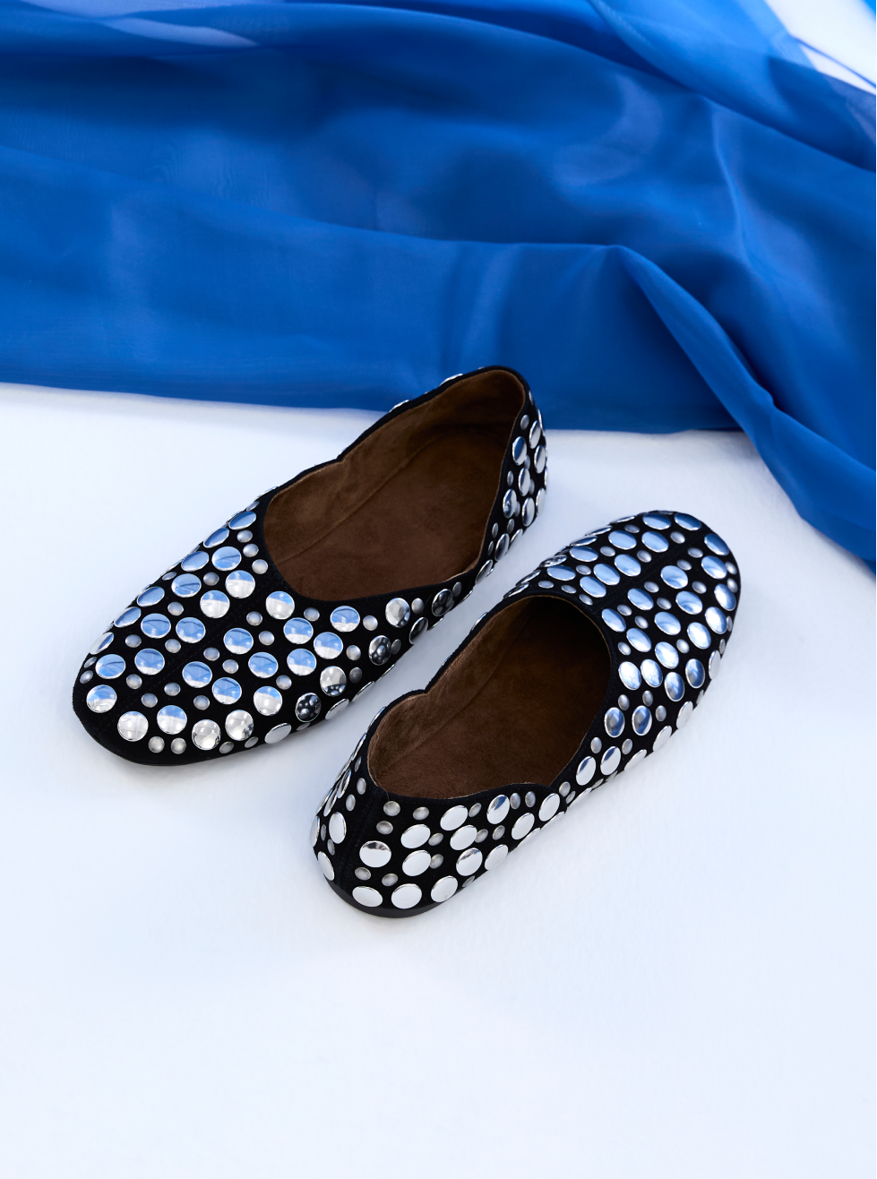 Black flats with white polka dot pattern on a blue fabric background