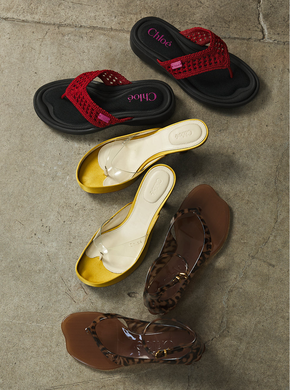 Set of Chloé sandals in black, red, yellow, and brown on a textured surface.