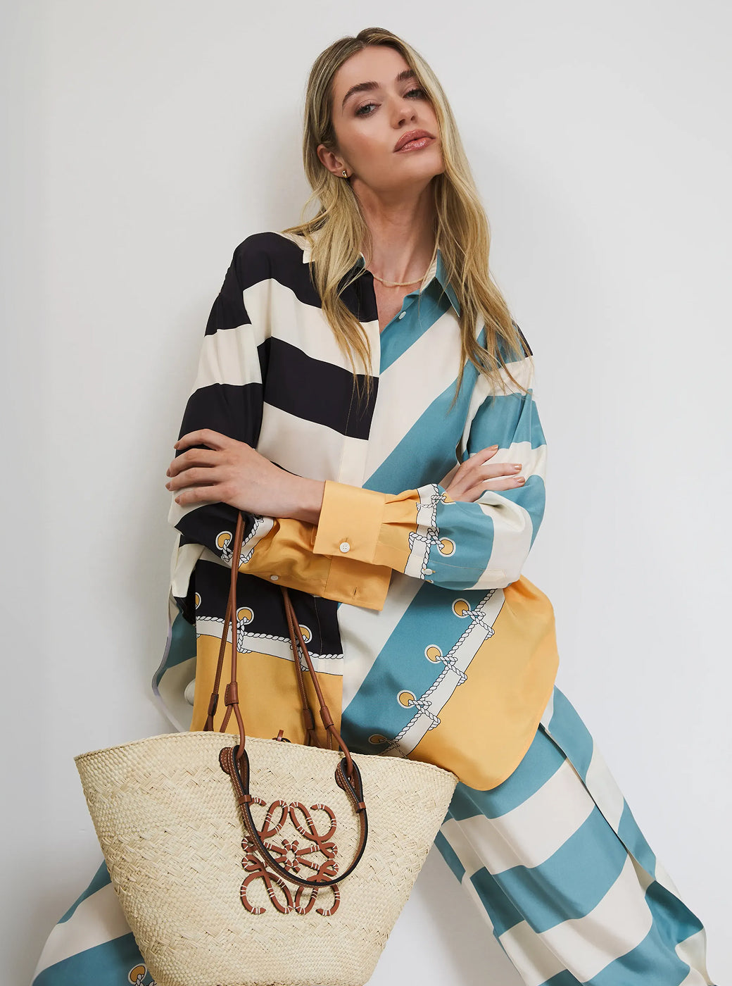 Woman wearing a colorful striped outfit with a yellow bag and straw tote.