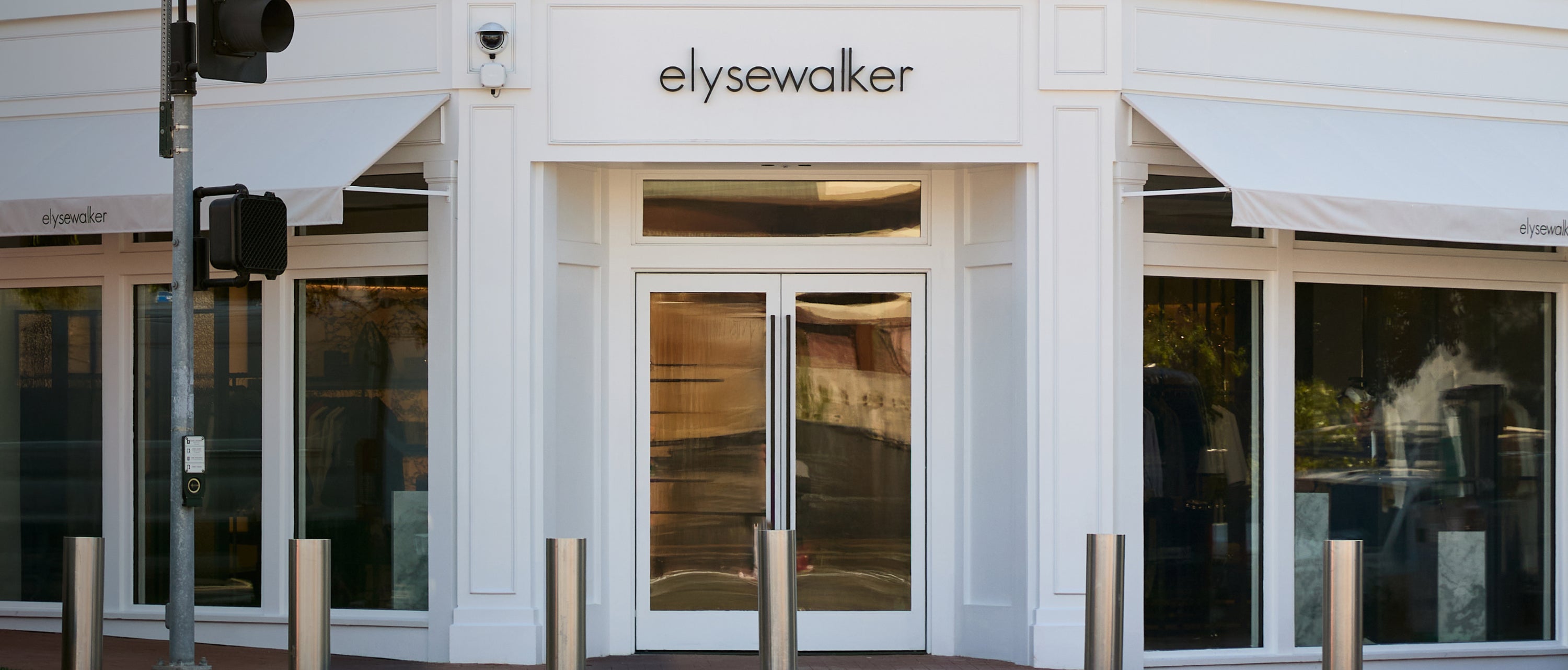 Elysewalker storefront with white facade, glass double doors, large windows, and a small sign above the entrance.